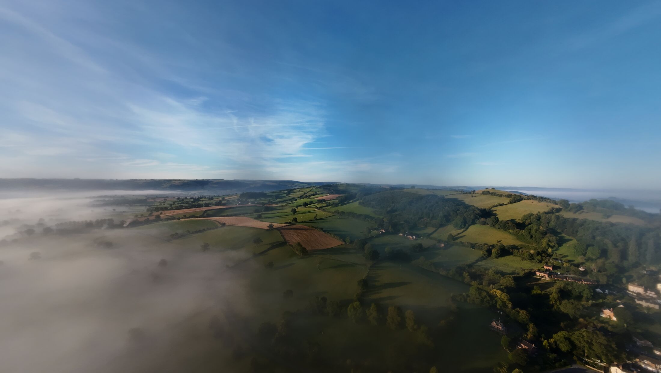 Dawn mist filling a Welsh valley, with hills rising above it into clear sky